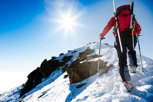 Mountaineer walking up along a snowy ridge with the skis in the